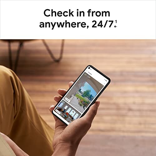 Person holding smartphone with home monitoring app.